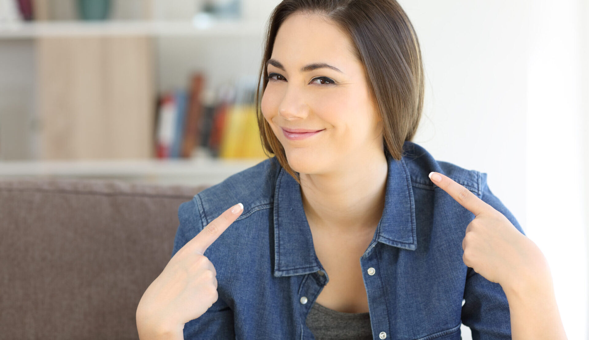 Woman playfully pointing at herself, symbolizing authentic self-promotion with confidence and humor