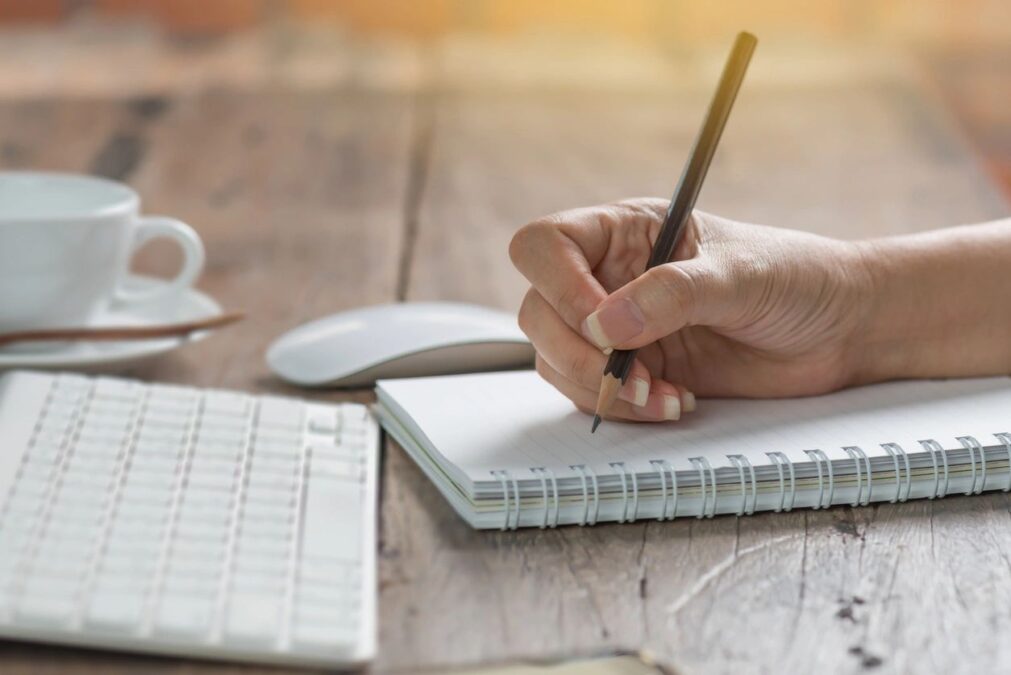 Woman's hand holding a pen, writing notes